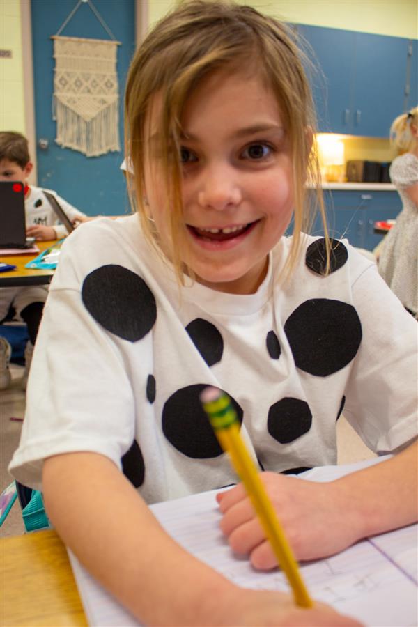 girl dressed as dalmatian dog writing with pencil